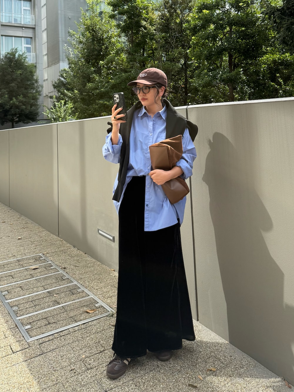 ブラック系のスカート、ブラウン系のスニーカー、ブラウン系のバッグを着用したレディースの秋コーディネートの2枚目の写真