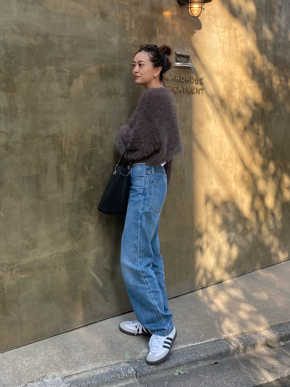 ブルー系のデニムパンツ、グレー系のニット/セーター、ブラック系のショルダーバッグを着用したレディースの秋コーディネートの2枚目の写真