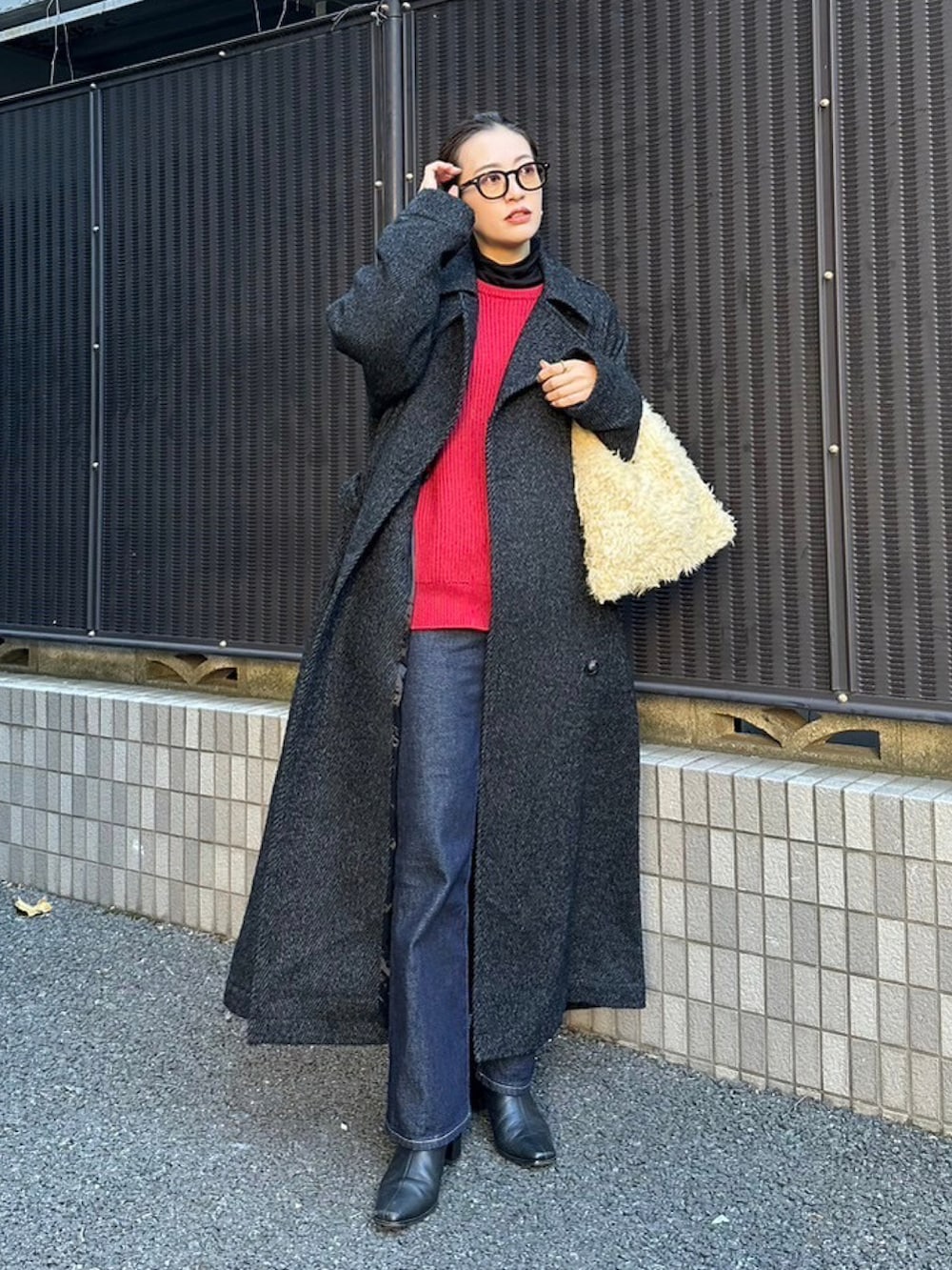 レッド系のニット/セーター、ベージュ系のトートバッグ、ブラック系のチェスターコートを着用したレディースの冬コーディネートの2枚目の写真