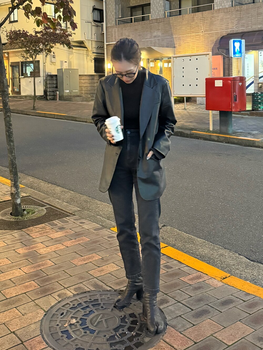 ブラック系のテーラードジャケット、ブラック系のニット/セーター、ブラック系のデニムパンツを着用したレディースの秋コーディネートの2枚目の写真