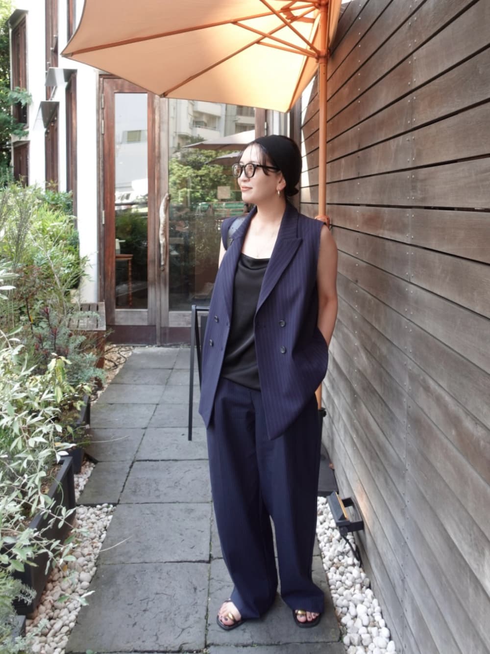 ブルー系のパンツ、ブラック系のサンダル、ブルー系のベストを着用したレディースの夏コーディネートの2枚目の写真