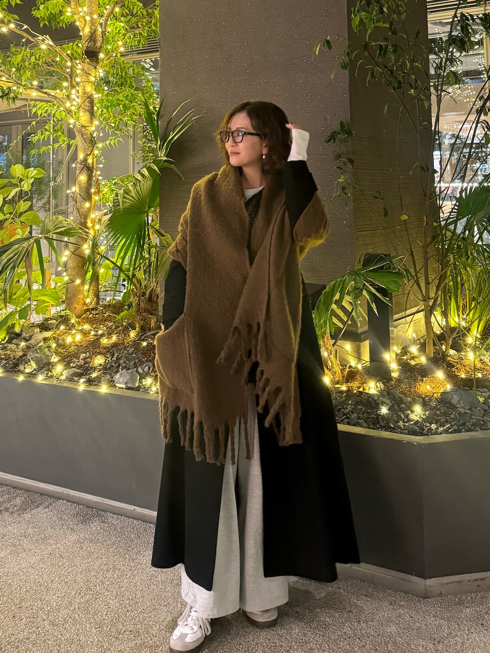 ブラック系のチェスターコート、グレー系のニット/セーター、ホワイト系のスニーカーを着用したレディースの冬コーディネートの3枚目の写真