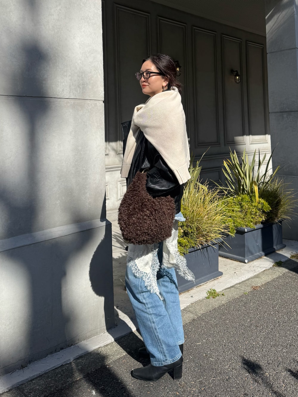 ブルー系のデニムパンツ、ブラック系のブーツ、ブラウン系のバッグを着用したレディースの冬コーディネートの2枚目の写真