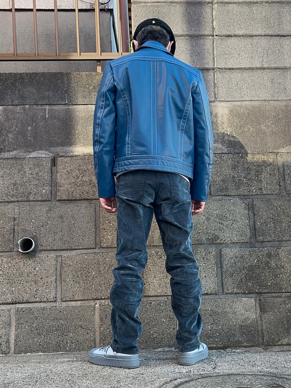 ブルー系のライダースジャケット、グレー系のスニーカー、ホワイト系のスウェットを着用したメンズの冬コーディネートの2枚目の写真