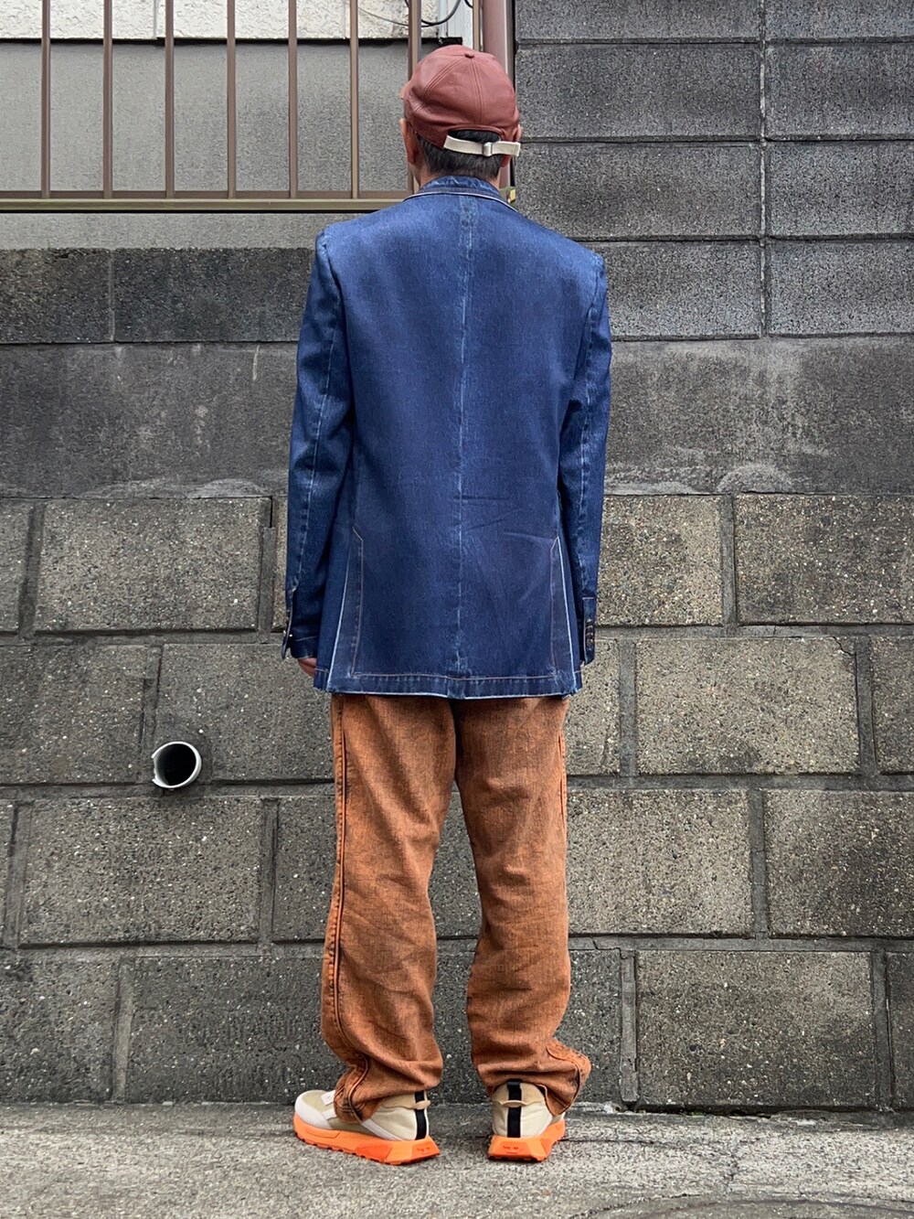 ブルー系のテーラードジャケット、オレンジ系のデニムパンツ、ホワイト系のスニーカーを着用したメンズの秋コーディネートの2枚目の写真
