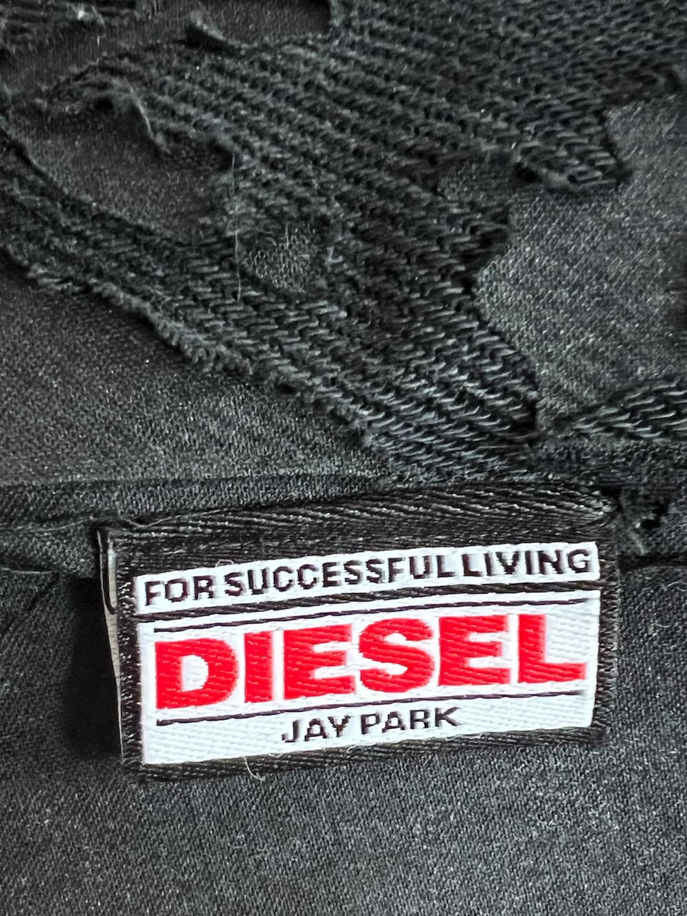 ブラック系のカバーオール、ベージュ系のニット/セーター、ブラック系のデニムパンツを着用したメンズの春コーディネートの3枚目の写真