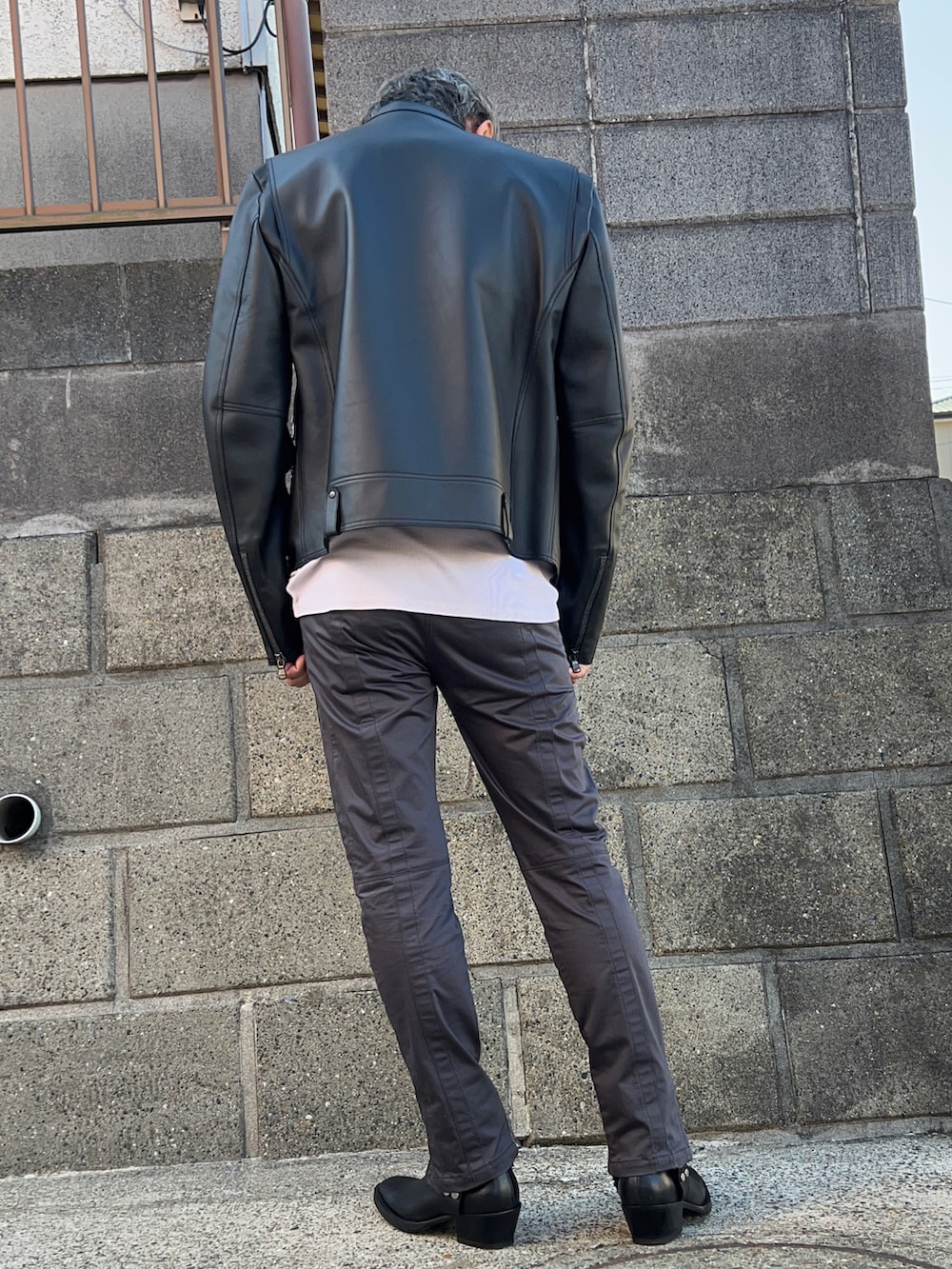 ブラック系のライダースジャケット、ブラック系のブーツ、ブラック系のパンツを着用したメンズの秋コーディネートの2枚目の写真