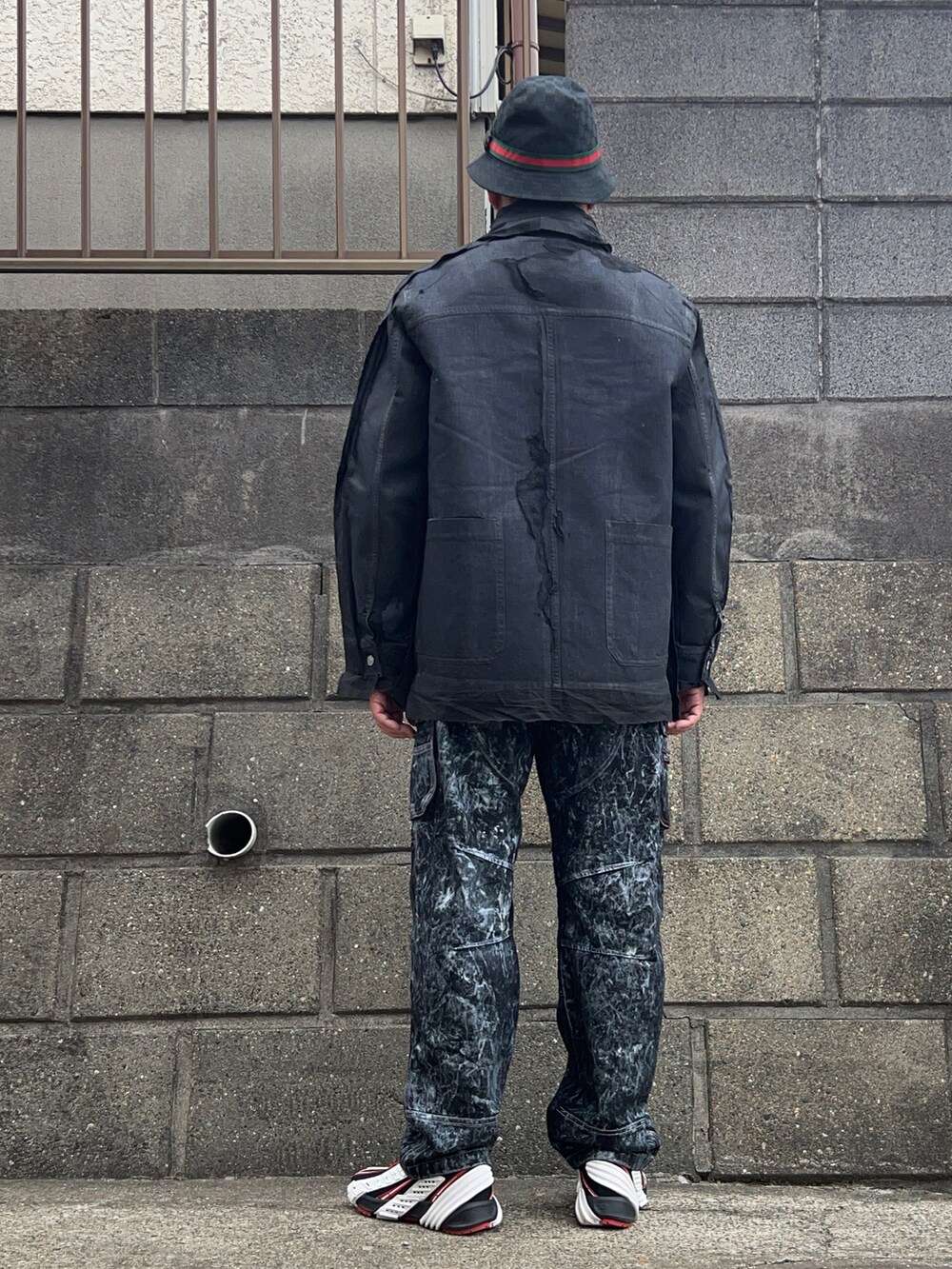 ブラック系のカバーオール、ベージュ系のニット/セーター、ブラック系のデニムパンツを着用したメンズの春コーディネートの2枚目の写真