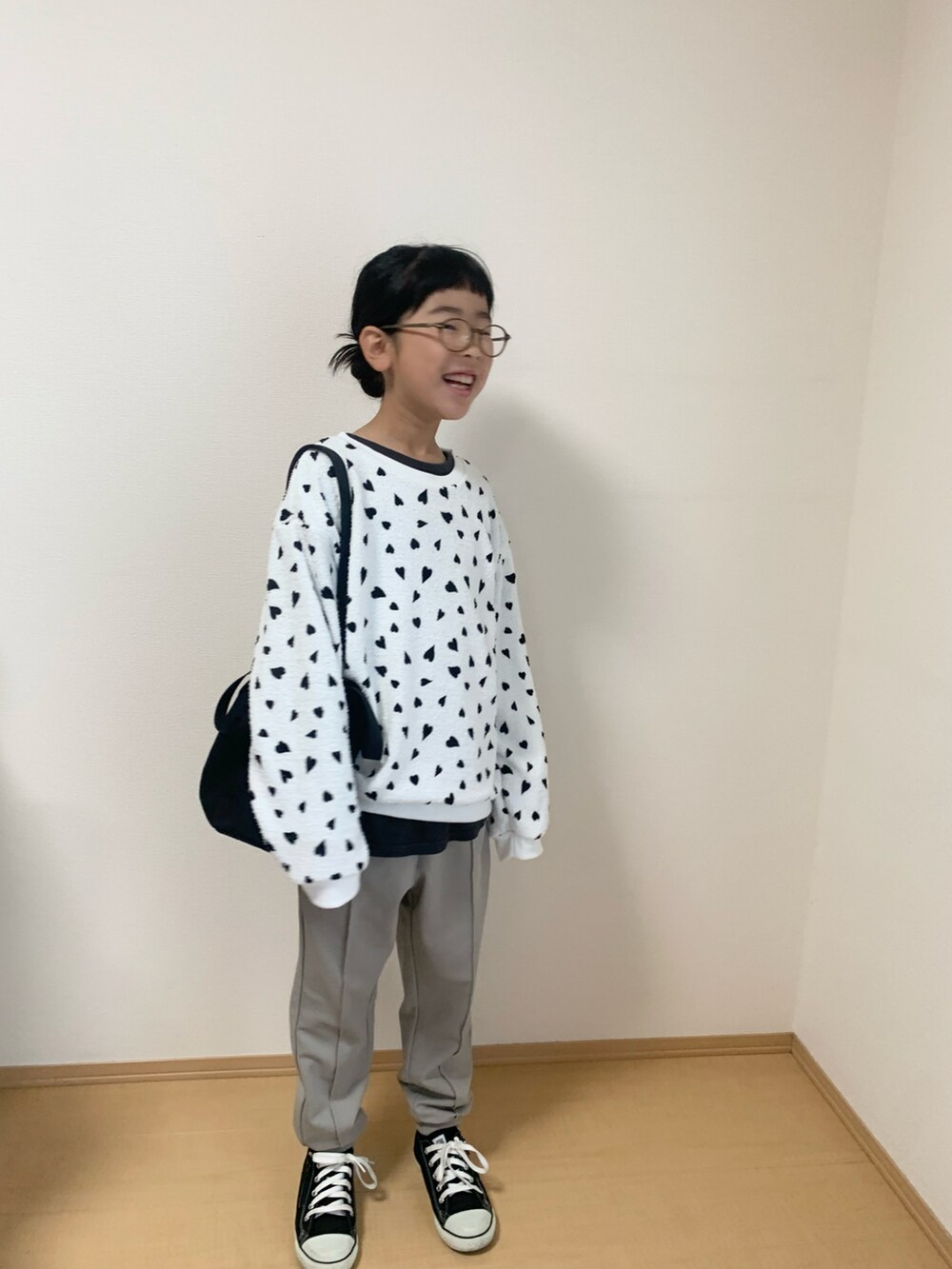 ホワイト系のトップス、グレー系のパンツ、ブラック系のスニーカーを着用したキッズの秋コーディネートの2枚目の写真
