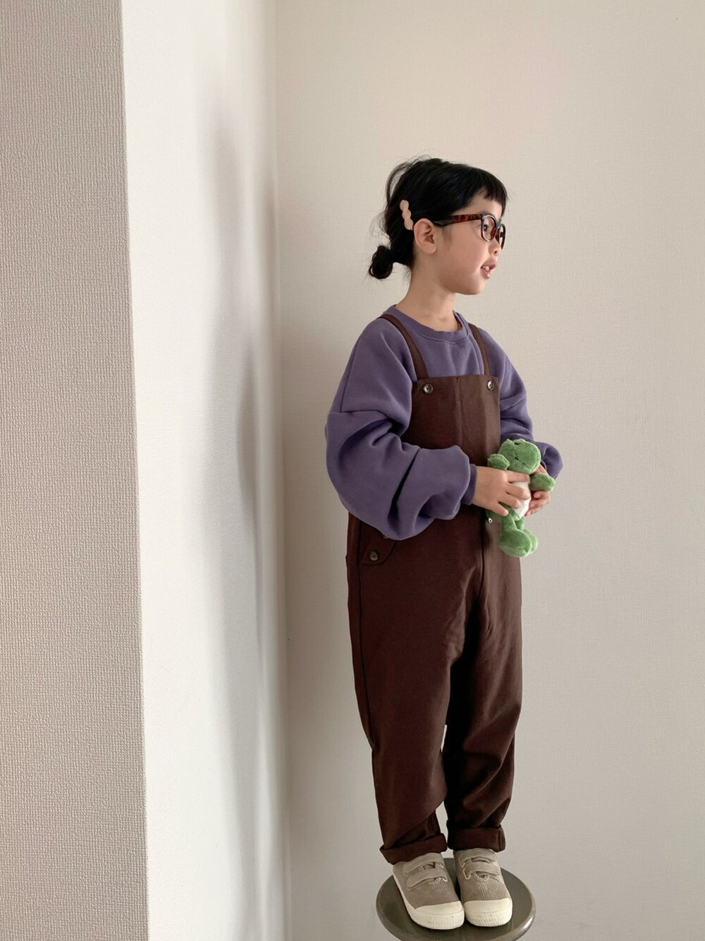 ブラウン系のサロペット/オーバーオール、パープル系のスウェット、ベージュ系のスニーカーを着用したキッズの冬コーディネートの2枚目の写真