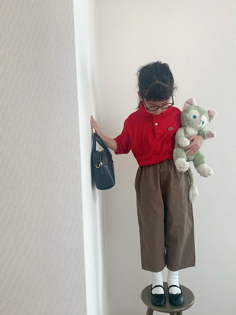 レッド系のポロシャツ、ブラック系のバレエシューズ、ブラック系のバッグを着用したキッズの春コーディネートの3枚目の写真