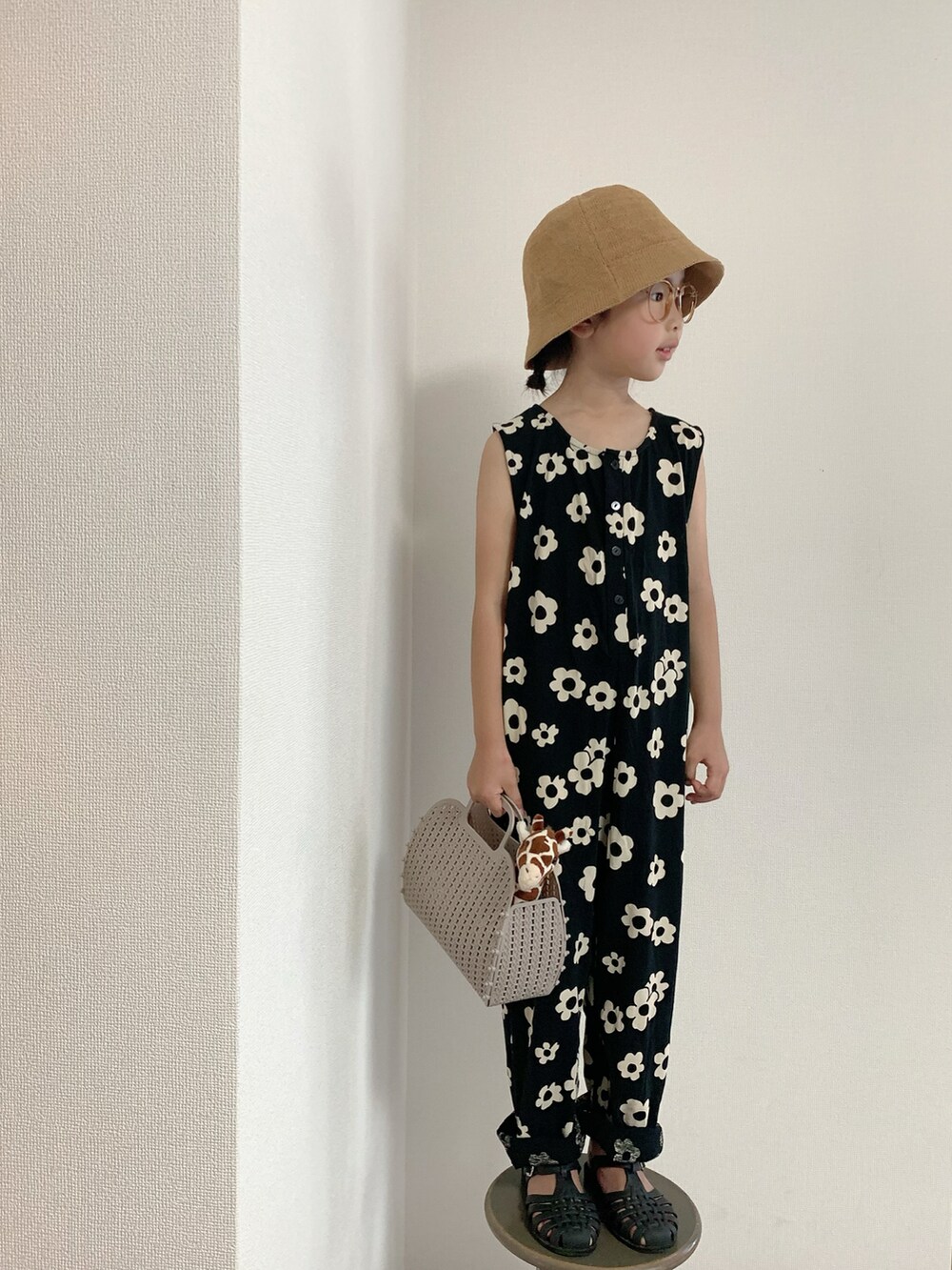 ベージュ系のバッグ、ブラック系のオールインワン・サロペット、ブラック系のサンダルを着用したキッズの夏コーディネートの2枚目の写真