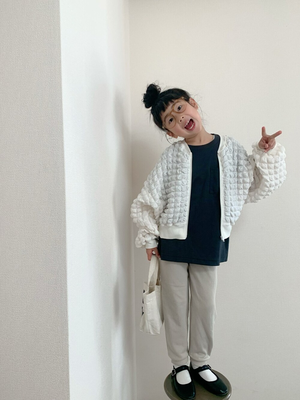 ホワイト系のジャケット/アウター、ブラック系のバレエシューズ、ブラック系のTシャツ/カットソーを着用したキッズの春コーディネートの2枚目の写真