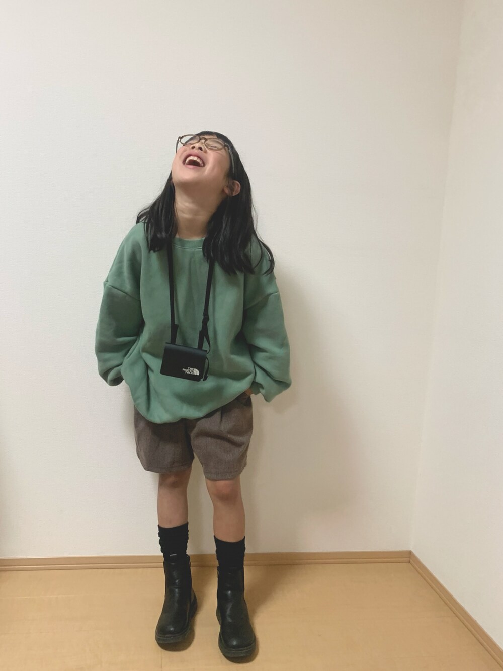 ブラウン系のパンツ、グリーン系のスウェット、ブラック系のショルダーバッグを着用したキッズの秋コーディネートの2枚目の写真