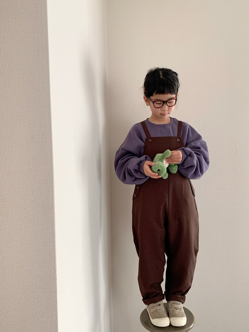 ブラウン系のサロペット/オーバーオール、パープル系のスウェット、ベージュ系のスニーカーを着用したキッズの冬コーディネートの3枚目の写真