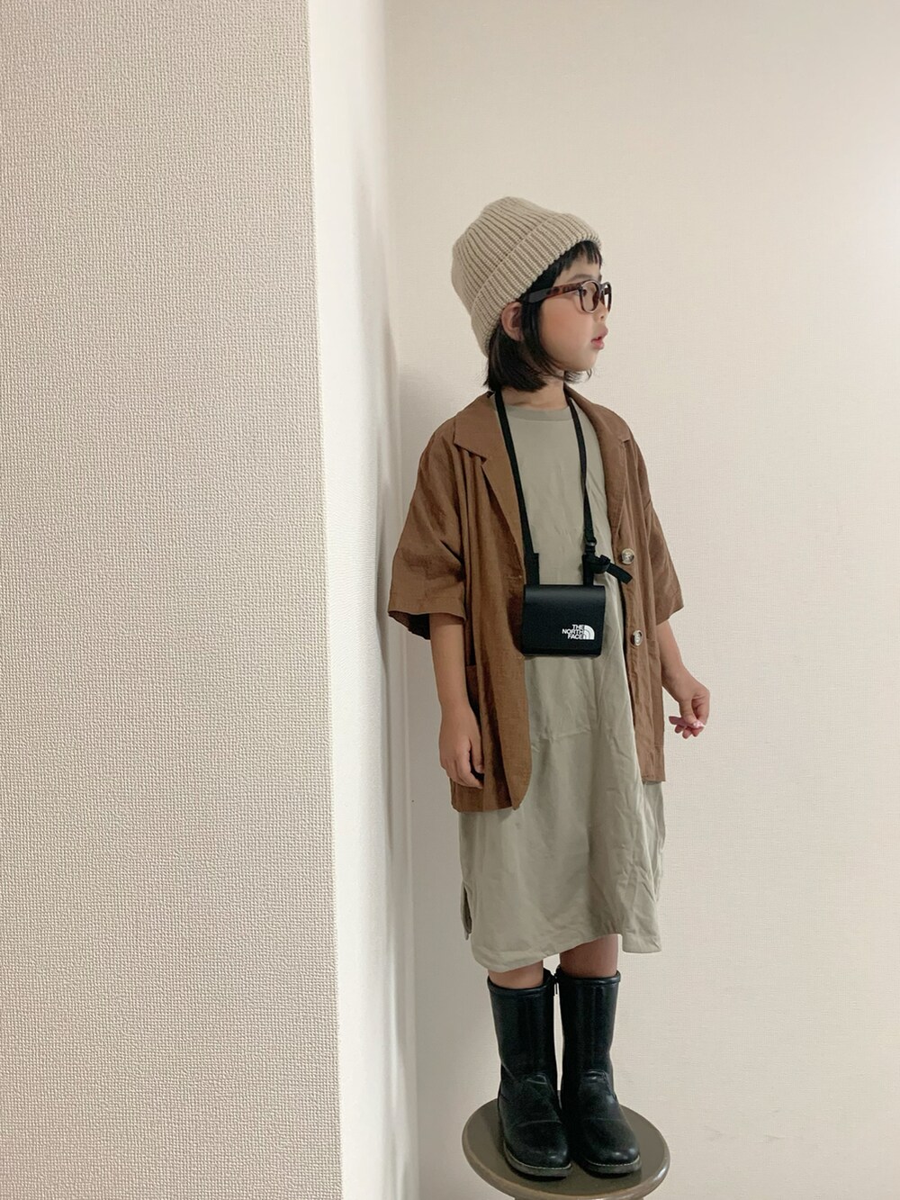 ブラック系のブーツ、ブラック系のショルダーバッグ、グリーン系のワンピース/ドレスを着用したキッズの秋コーディネートの2枚目の写真