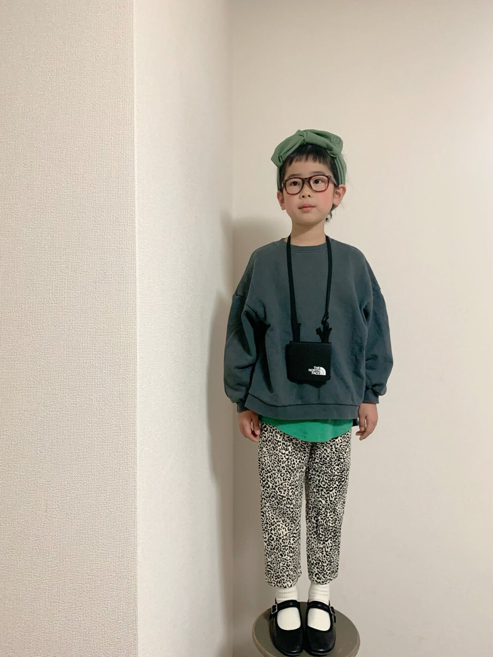 ホワイト系のパンツ、ブラック系のバレエシューズ、グリーン系のTシャツ/カットソーを着用したキッズの冬コーディネートの2枚目の写真