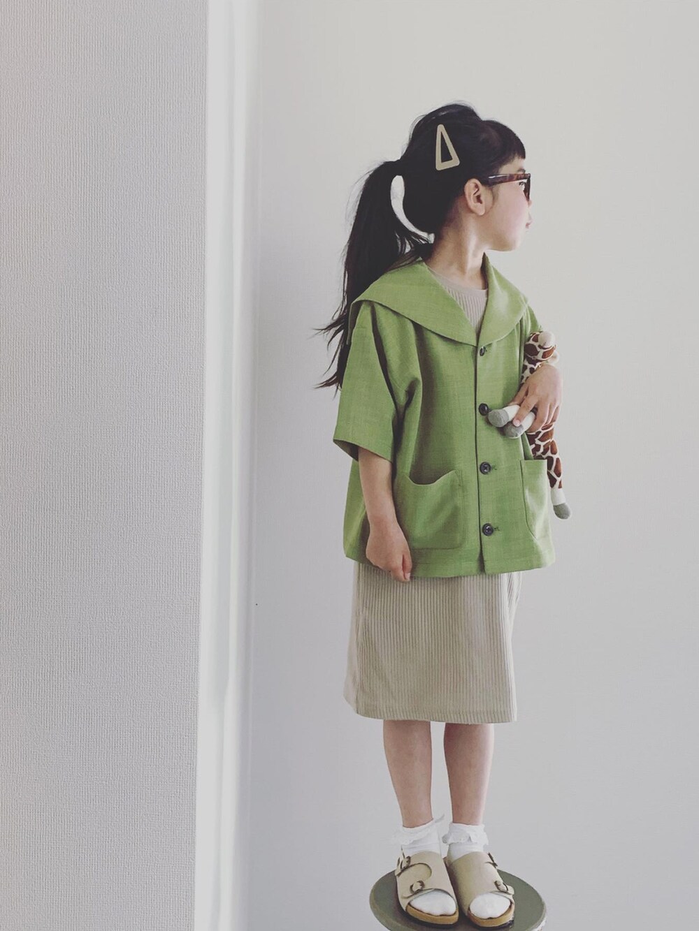 グリーン系のテーラードジャケット、ベージュ系のワンピース/ドレス、ベージュ系のサンダルを着用したキッズの春コーディネートの2枚目の写真