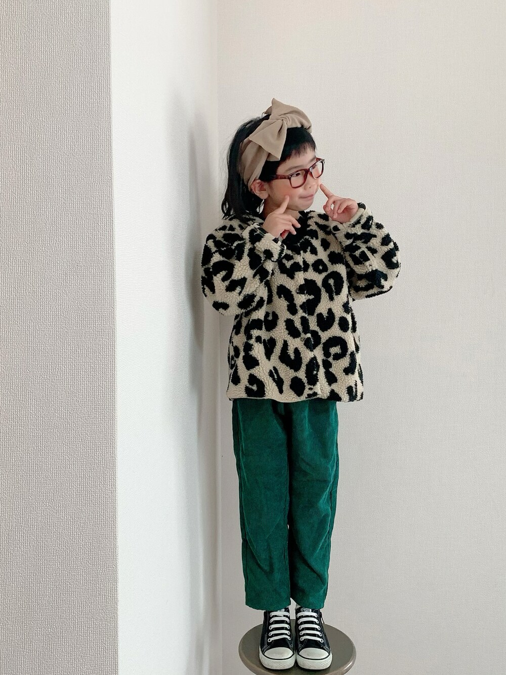 グリーン系のパンツ、ブラック系のスニーカー、ベージュ系のヘアバンドを着用したキッズの秋コーディネートの2枚目の写真