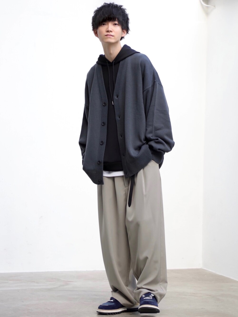 グレー系のカーディガン/ボレロ、ブラック系のパーカー、グレー系のスラックスを着用したメンズの冬コーディネートの2枚目の写真