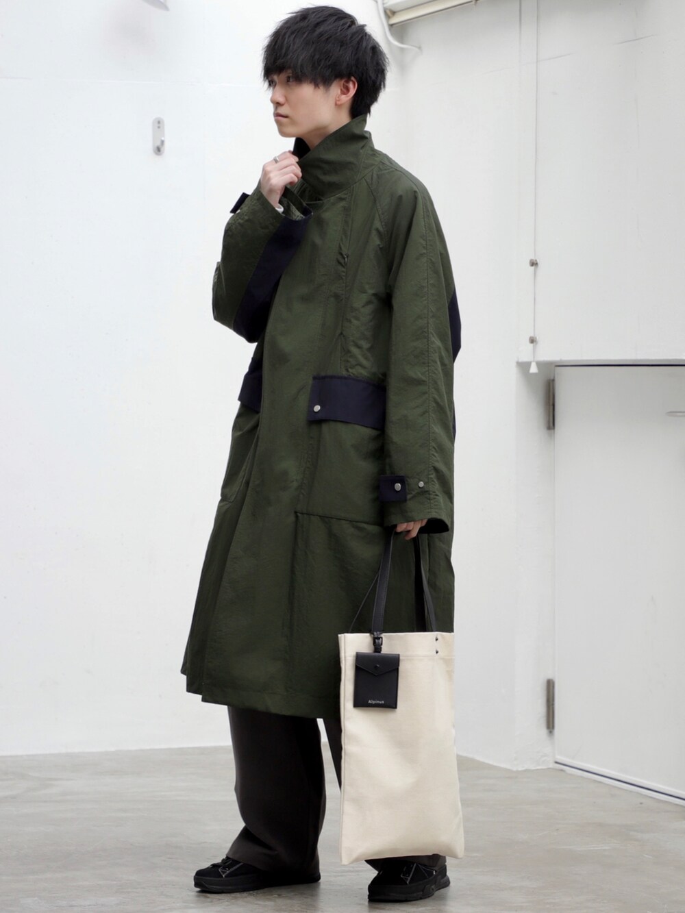 グリーン系のトレンチコート、ホワイト系のスウェット、ホワイト系のトートバッグを着用したメンズの秋コーディネートの3枚目の写真