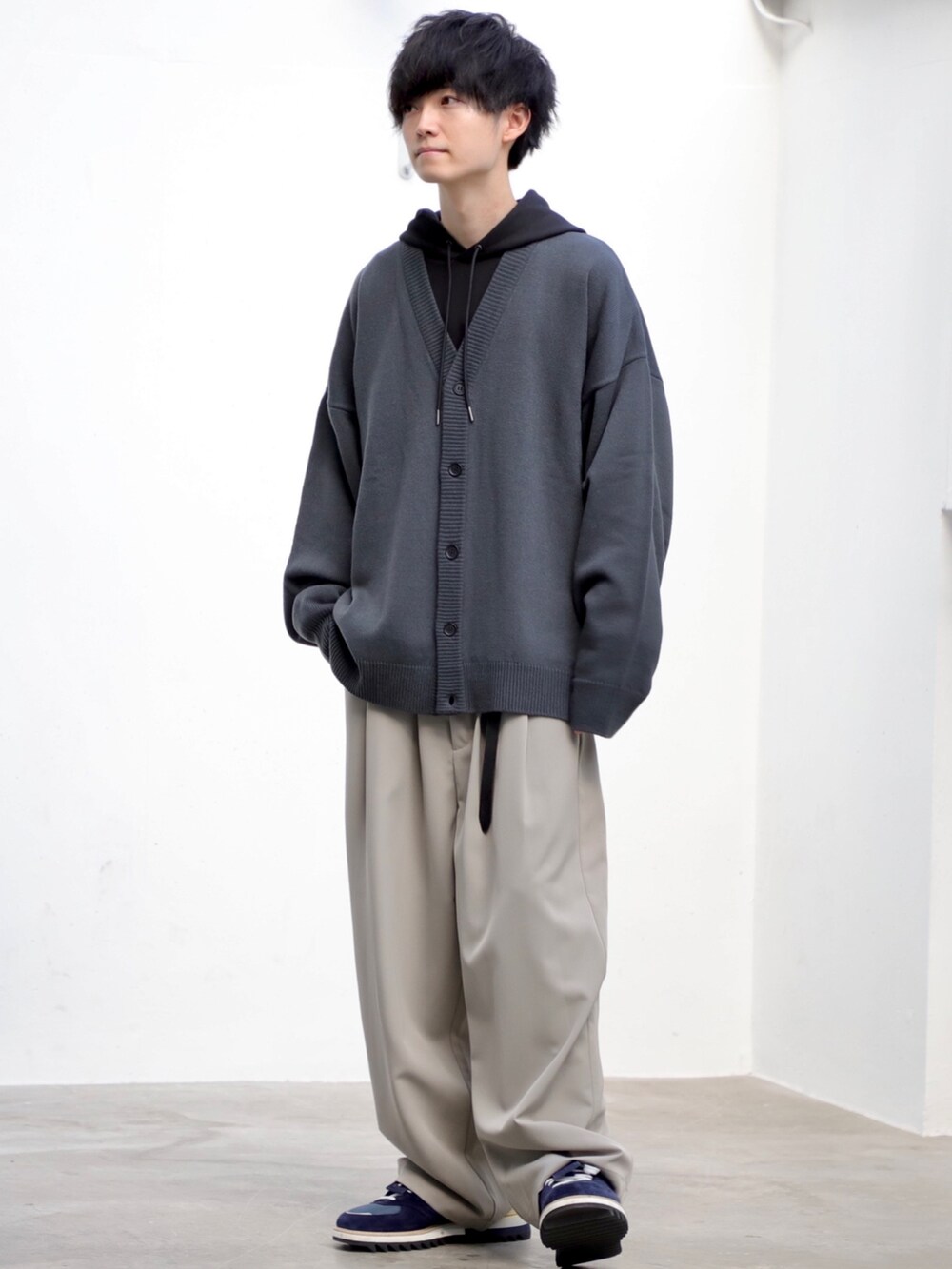 ブラック系のパーカー、グレー系のスラックス、ブルー系のスニーカーを着用したメンズの冬コーディネートの2枚目の写真