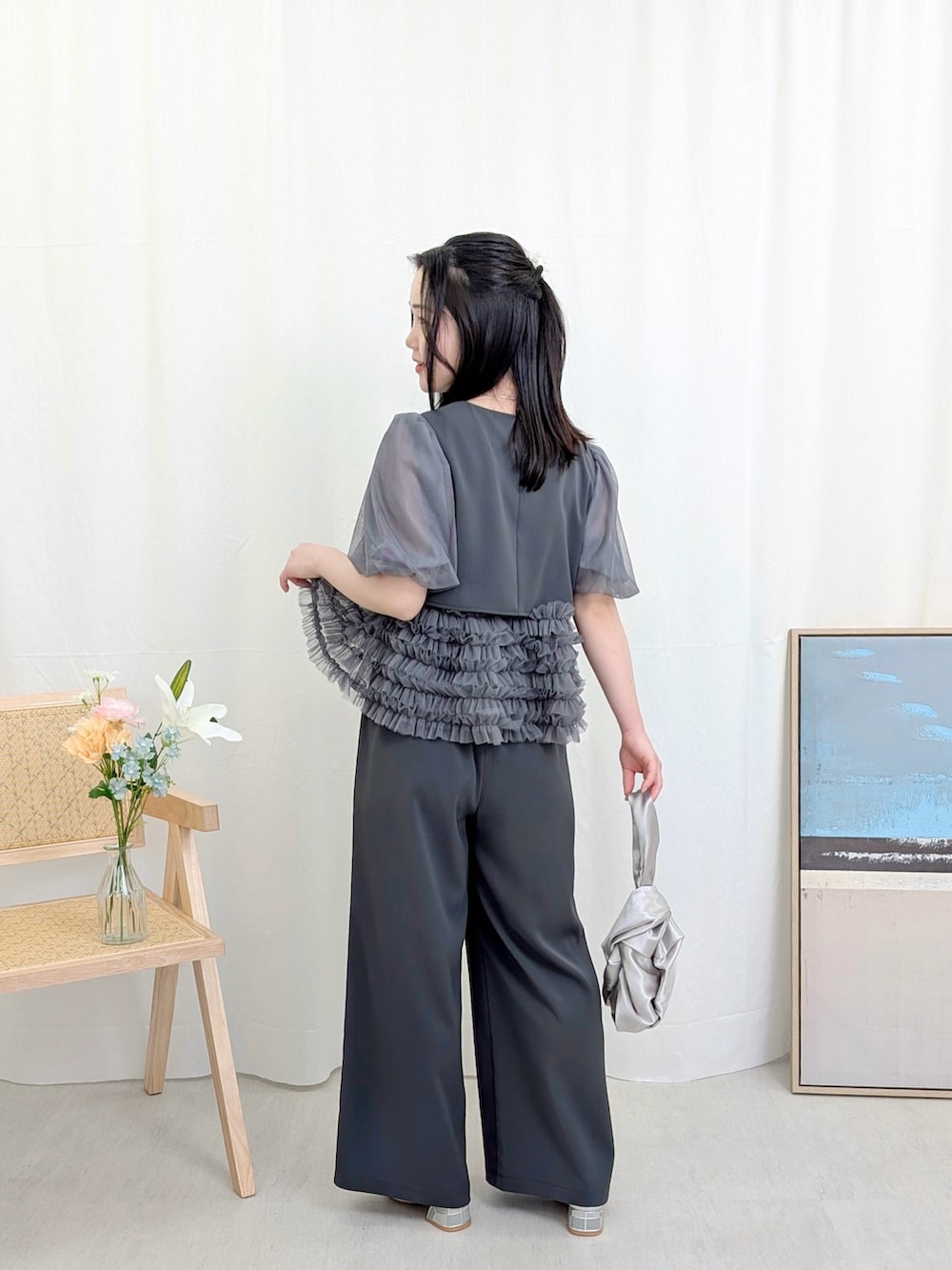 グレー系のパンツドレス、シルバー系のハンドバッグ、シルバー系のパンプスを着用したレディースの春コーディネートの3枚目の写真