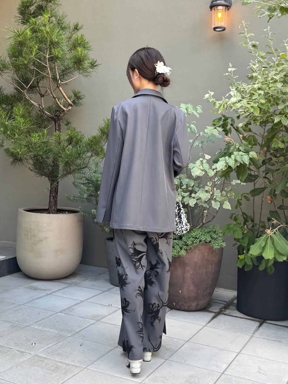 シルバー系のパンプス、グレー系のパンツドレス、ブラック系のハンドバッグを着用したレディースの夏コーディネートの2枚目の写真