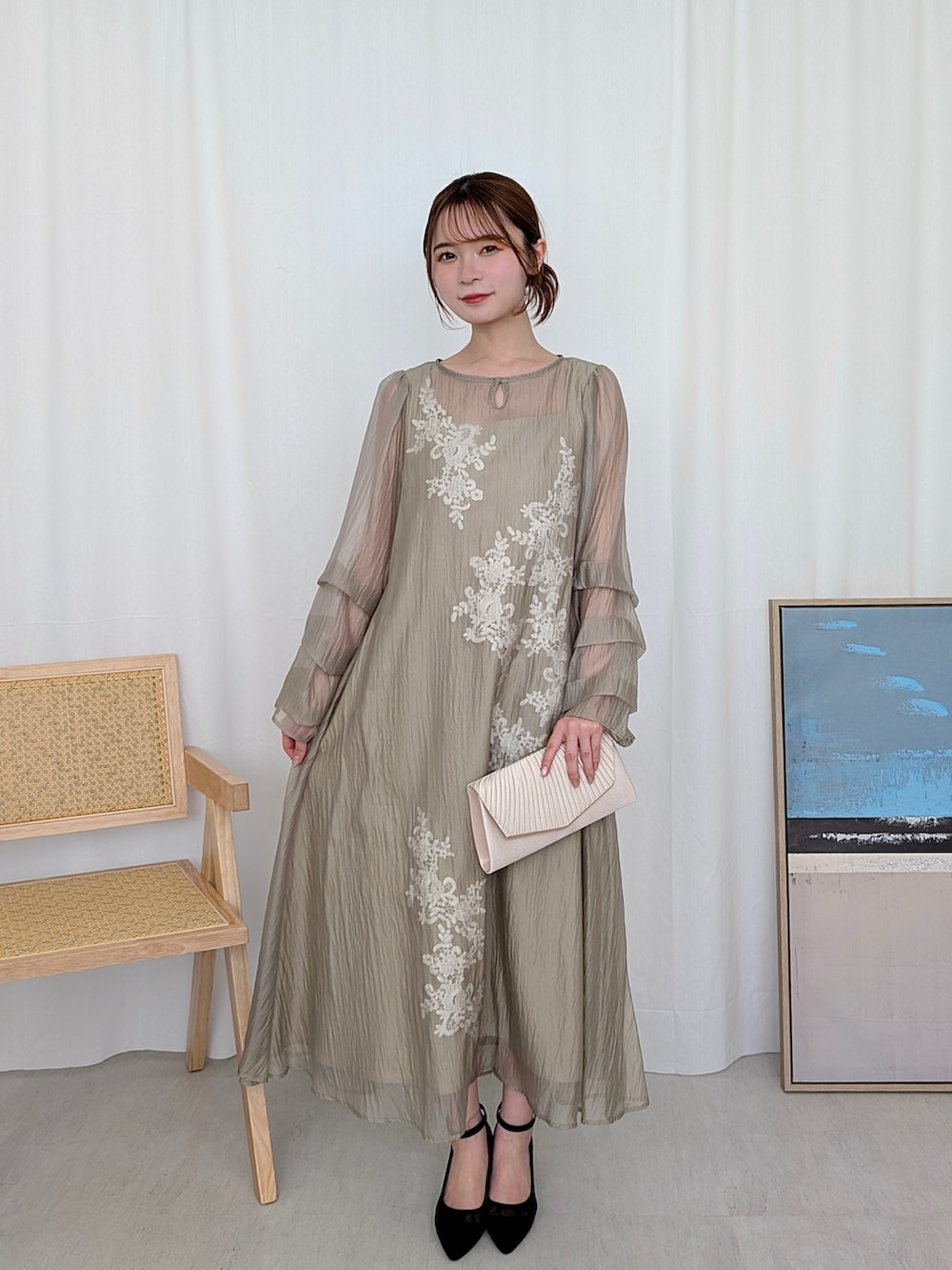 イエロー系のドレス、ベージュ系のクラッチバッグを着用したレディースの春コーディネートの2枚目の写真