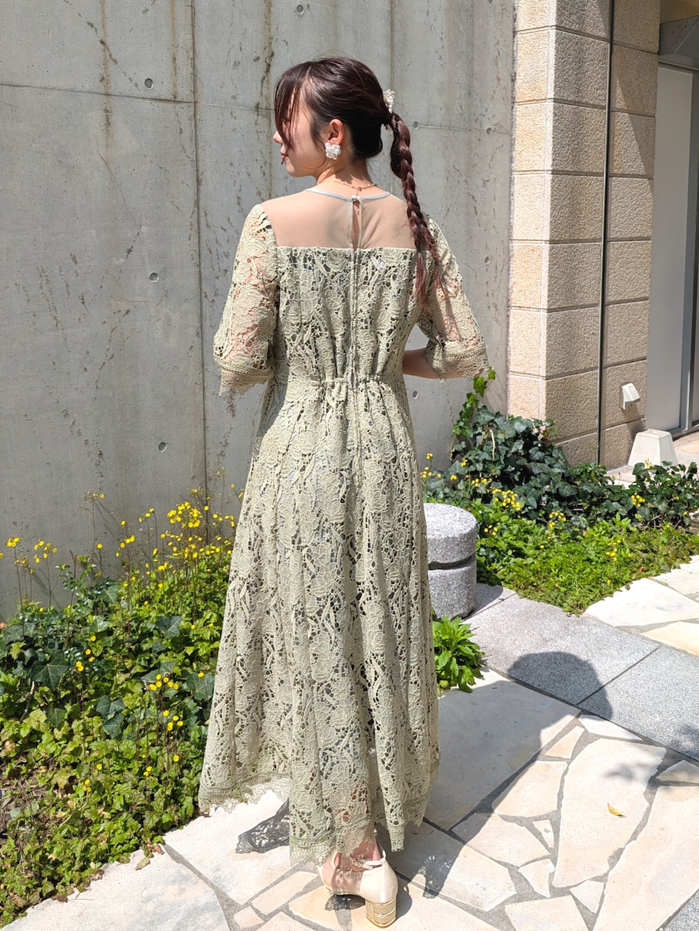 グリーン系のドレス、ベージュ系のパンプス、ベージュ系のクラッチバッグを着用したレディースの春コーディネートの2枚目の写真