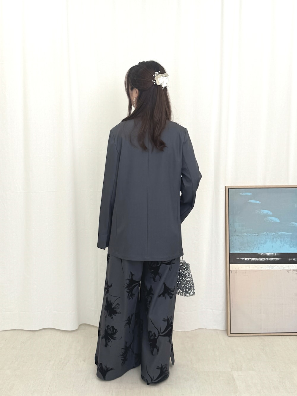 グレー系のパンツドレス、ブラック系のバッグを着用したレディースの秋コーディネートの2枚目の写真