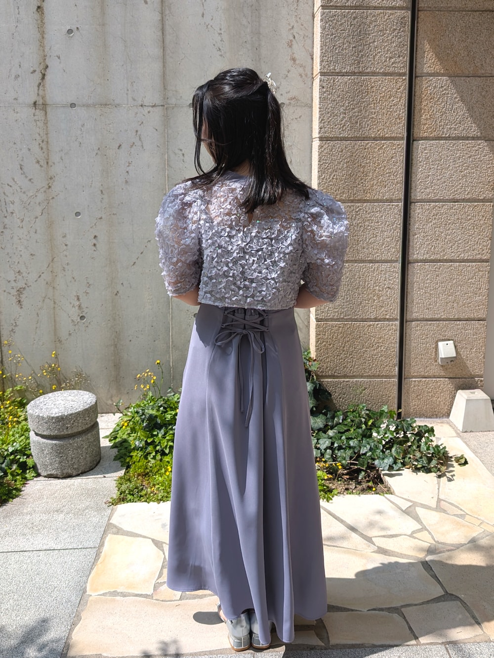 ブルー系のドレス、ベージュ系のクラッチバッグを着用したレディースの春コーディネートの2枚目の写真
