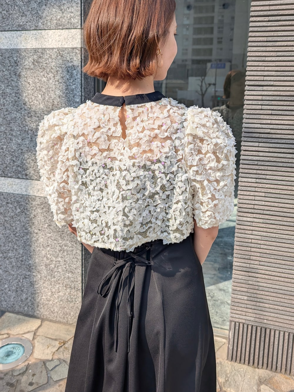 ブラック系のドレス、ブラック系のパンプス、ブラック系のバッグを着用したレディースの春コーディネートの3枚目の写真