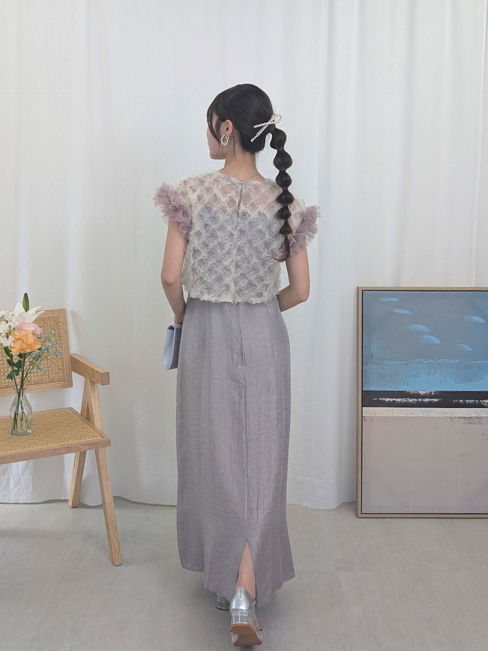 パープル系のドレス、シルバー系のパンプス、シルバー系のクラッチバッグを着用したレディースの春コーディネートの2枚目の写真