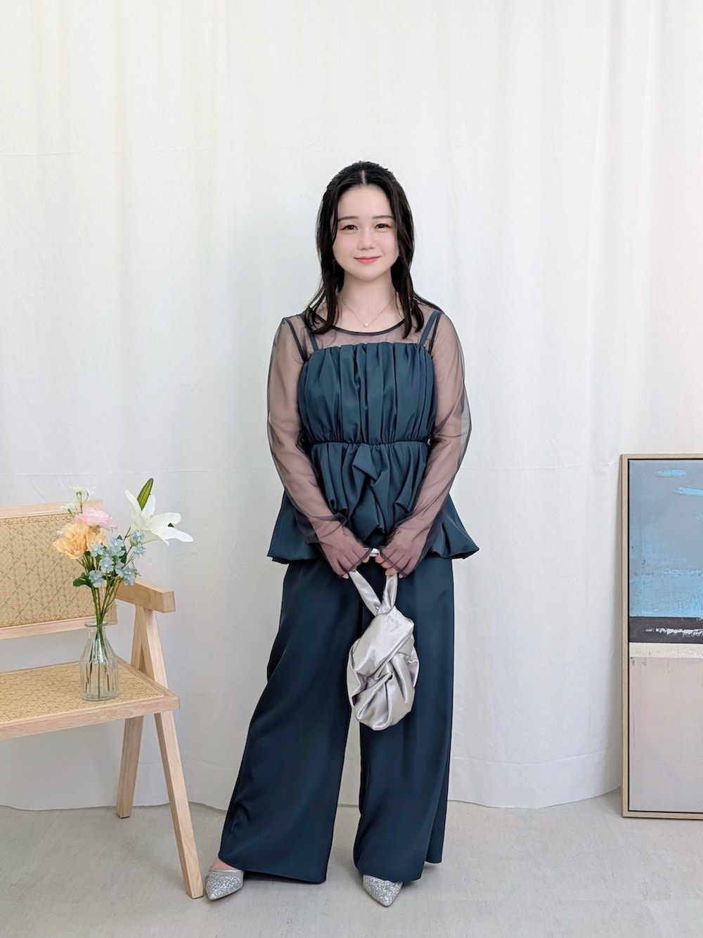 シルバー系のハンドバッグ、ブルー系のパンツドレスを着用したレディースの春コーディネートの2枚目の写真