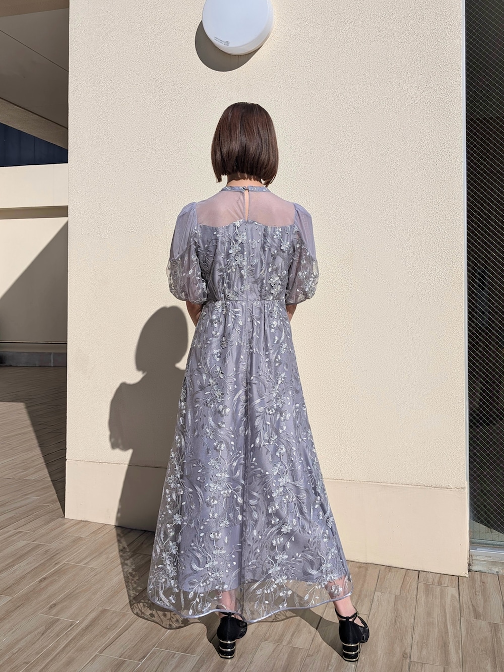 ブラック系のクラッチバッグ、ブラック系のパンプス、グレー系のドレスを着用したレディースの冬コーディネートの2枚目の写真