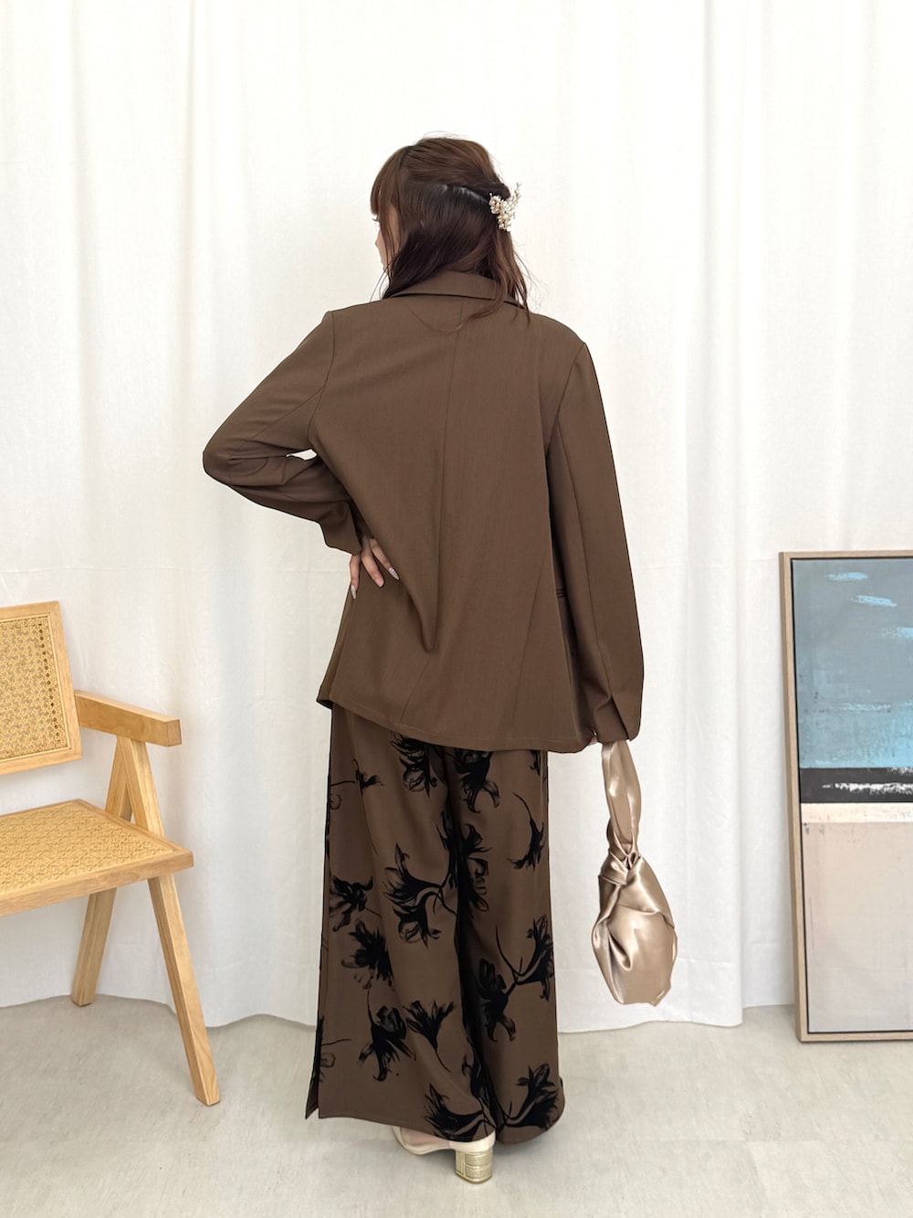 シルバー系のハンドバッグ、ベージュ系のパンプス、ブラウン系のパンツドレスを着用したレディースの夏コーディネートの2枚目の写真