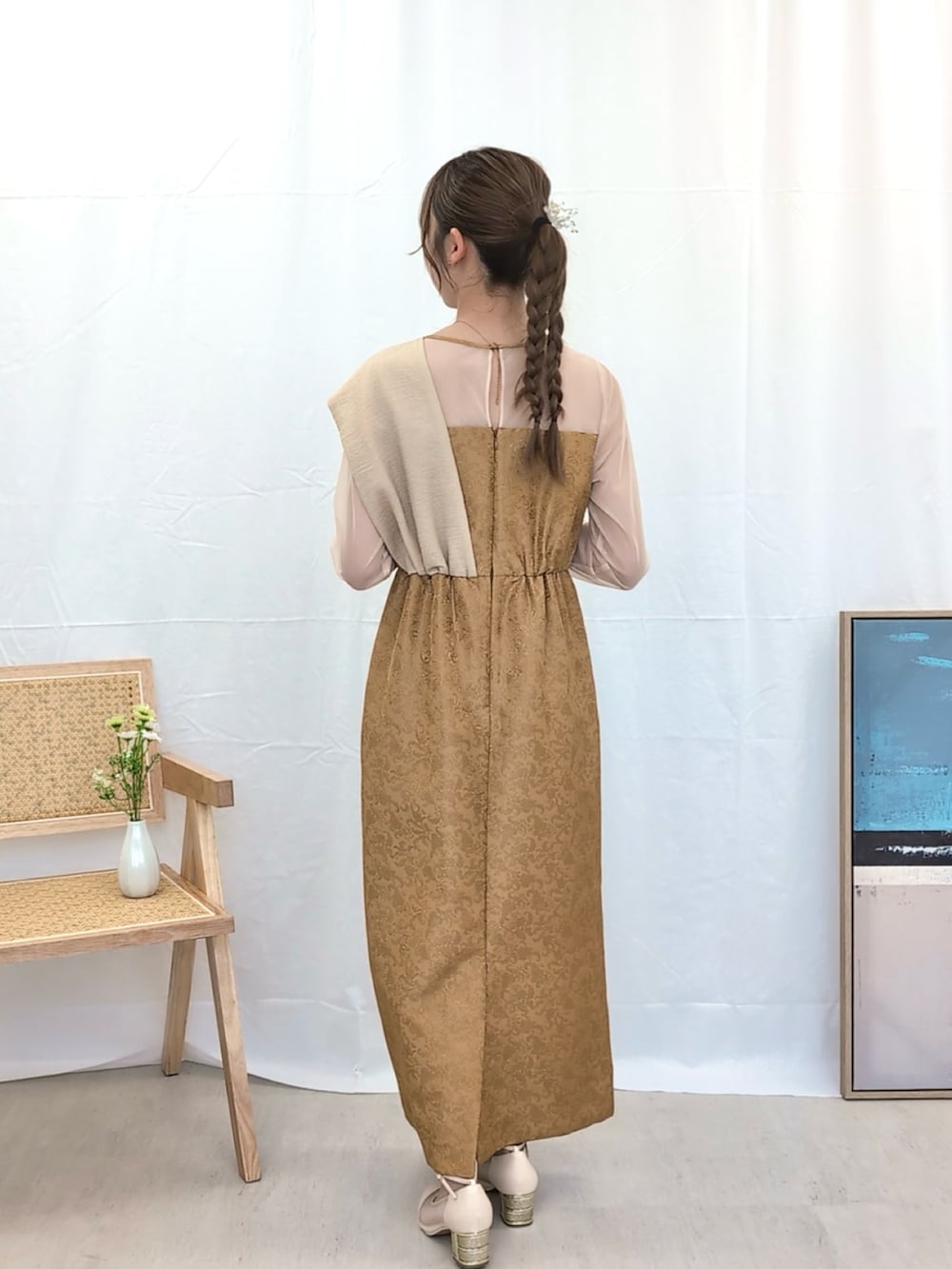 イエロー系のドレス、ベージュ系のクラッチバッグ、ベージュ系のパンプスを着用したレディースの冬コーディネートの2枚目の写真