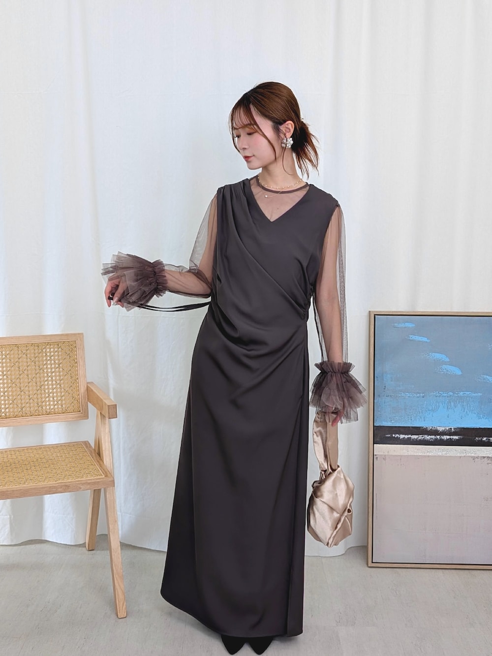 グレー系のドレス、ゴールド系のハンドバッグを着用したレディースの春コーディネートの2枚目の写真