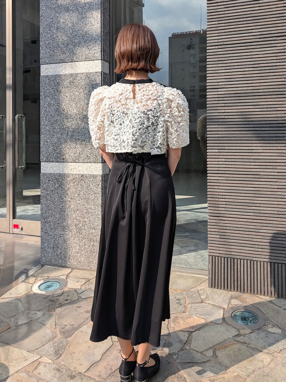 ブラック系のドレス、ブラック系のパンプス、ブラック系のバッグを着用したレディースの春コーディネートの2枚目の写真