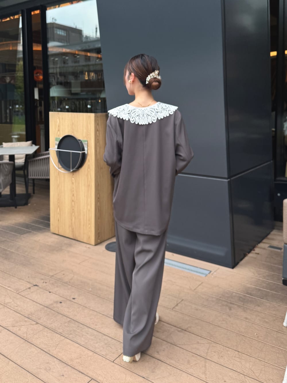 ブラウン系のパンツドレス、ゴールド系のハンドバッグを着用したレディースの秋コーディネートの2枚目の写真