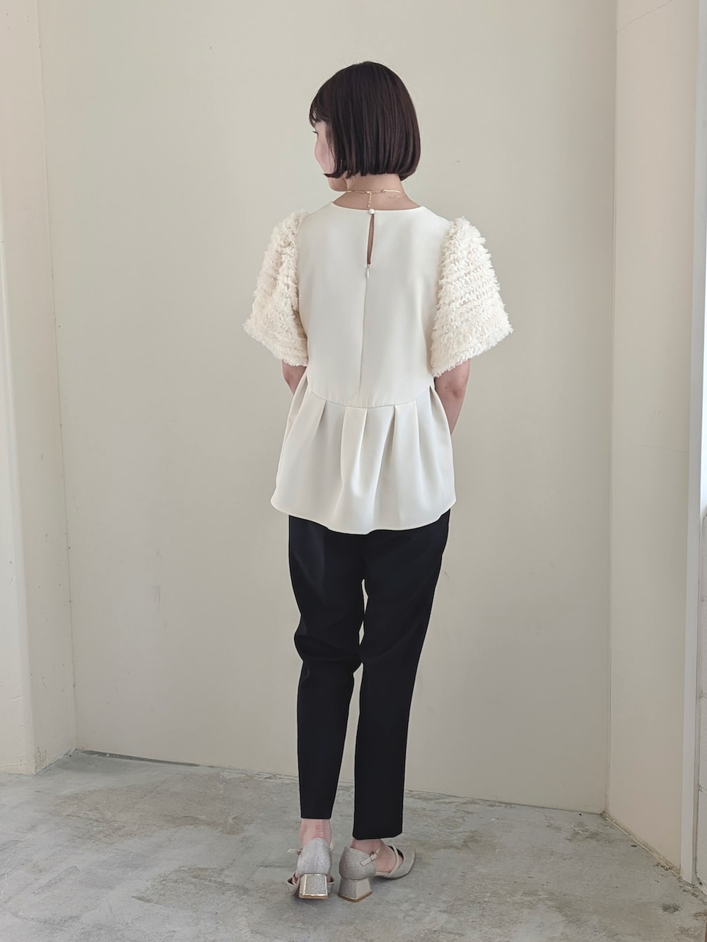 ホワイト系のパンツドレス、ホワイト系のハンドバッグ、ベージュ系のドレスシューズを着用したレディースの冬コーディネートの2枚目の写真