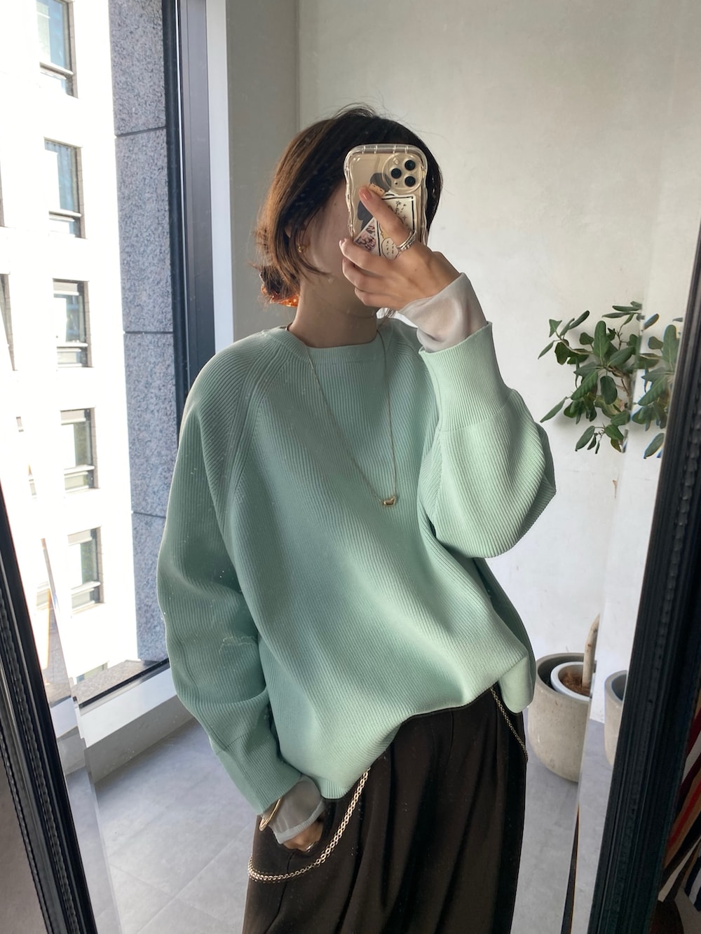 グリーン系のニット/セーター、ブラウン系のスラックス、グレー系のTシャツ/カットソーを着用したレディースの冬コーディネートの9枚目の写真