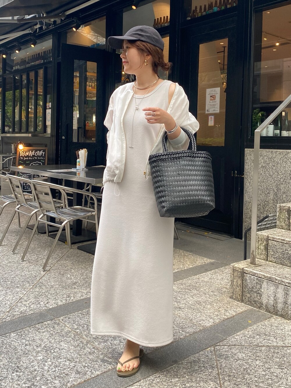 ベージュ系のワンピース、ホワイト系のブルゾン、ブラック系のかごバッグを着用したレディースの春コーディネートの6枚目の写真