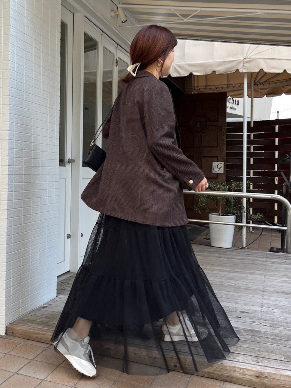 ブラウン系のテーラードジャケット、ブラック系のスカート、ブラック系のショルダーバッグを着用したレディースの秋コーディネートの10枚目の写真