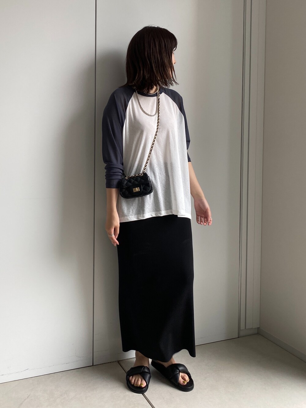 ホワイト系のTシャツ/カットソー、ブラック系のスカート、ブラック系のショルダーバッグを着用したレディースの夏コーディネートの2枚目の写真