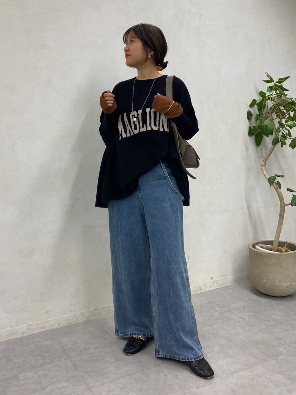 ブラック系のニット/セーター、ブルー系のデニムパンツ、ブラウン系のTシャツ/カットソーを着用したレディースの冬コーディネートの9枚目の写真