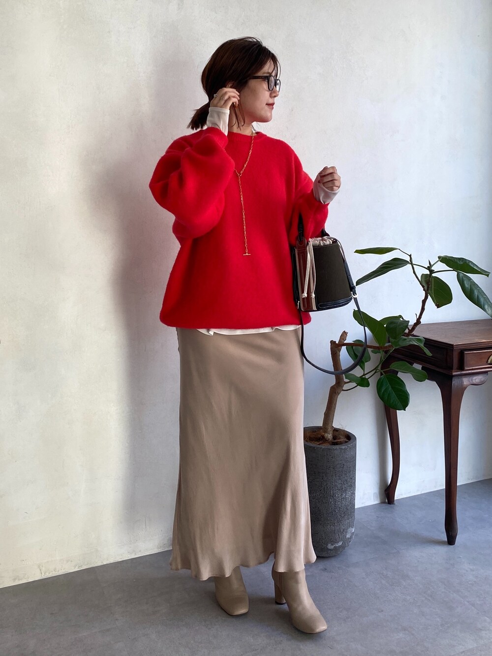 レッド系のニット/セーター、ホワイト系のTシャツ/カットソー、ベージュ系のスカートを着用したレディースの秋コーディネートの5枚目の写真