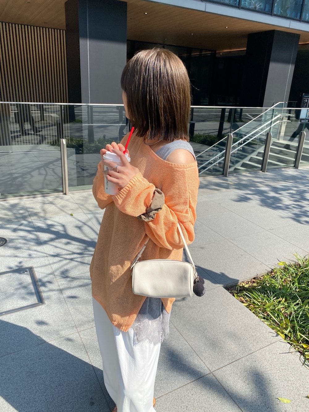 オレンジ系のニット/セーター、グレー系のTシャツ/カットソー、ホワイト系のその他パンツを着用したレディースの春コーディネートの4枚目の写真