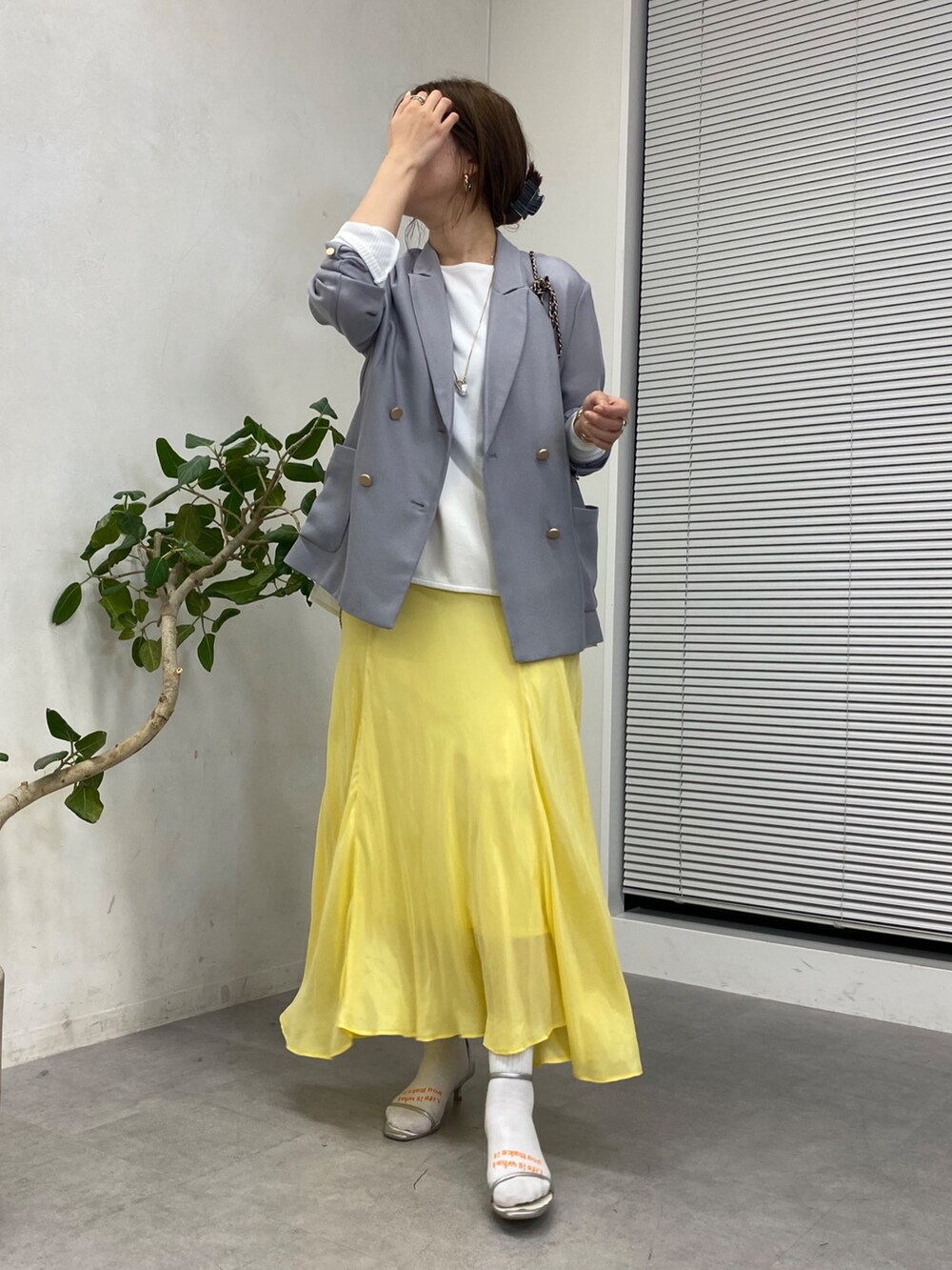 イエロー系のスカート、ホワイト系のシャツ/ブラウス、ブラック系のショルダーバッグを着用したレディースの冬コーディネートの2枚目の写真